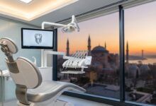 Interno di una clinica dentistica ultramoderna e sterile, con una poltrona odontoiatrica e monitor in primo piano. Sullo sfondo, una grande finestra offre una vista panoramica e sfocata di Istanbul al sorgere del sole.