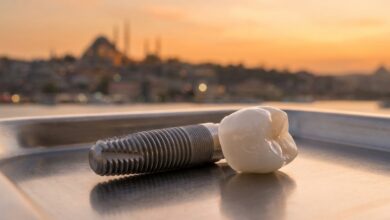 Immagine fotorealistica di un impianto dentale in titanio e una corona in zirconio in primo piano, con una vista panoramica sfocata di Istanbul al tramonto sullo sfondo, a rappresentare il turismo dentale in Turchia.