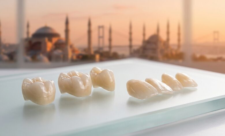 Un'immagine di corone e faccette dentali in ceramica di alta qualità in primo piano, con lo skyline di Istanbul sfocato sullo sfondo al tramonto, a simboleggiare l'eccellenza del turismo dentale in Turchia.