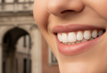 Primo piano fotorealistico di un sorriso luminoso e sano con denti bianchi e allineati, con un'architettura italiana classica sfocata sullo sfondo.